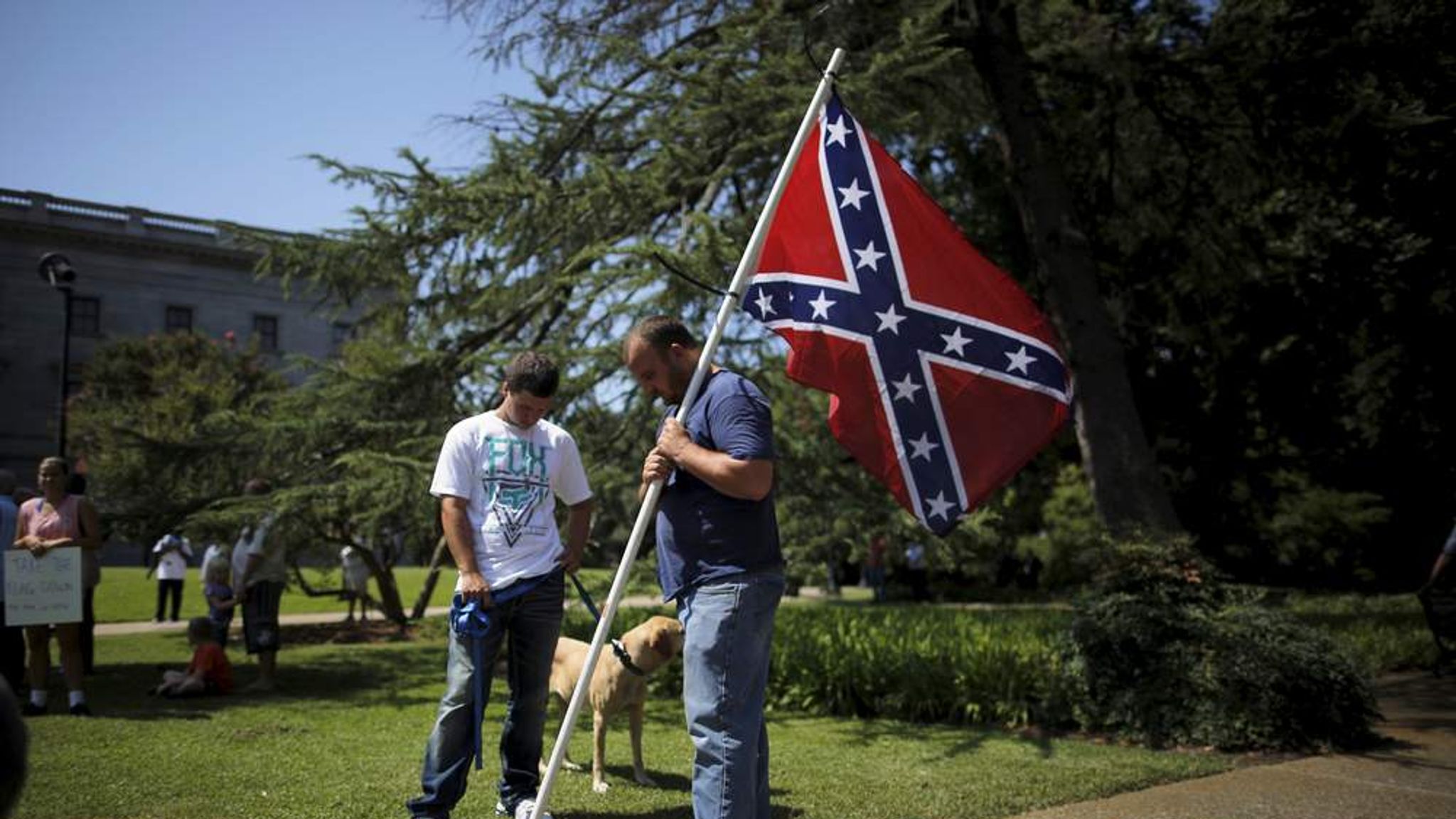 A man holds a Confederate flag during a prayer at a rally outside the State...