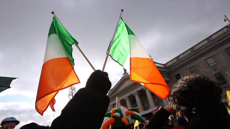 A protester holds up two Irish flags in.