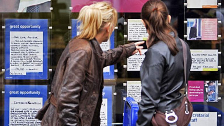 Women look at adverts in the window of an employment agency in London