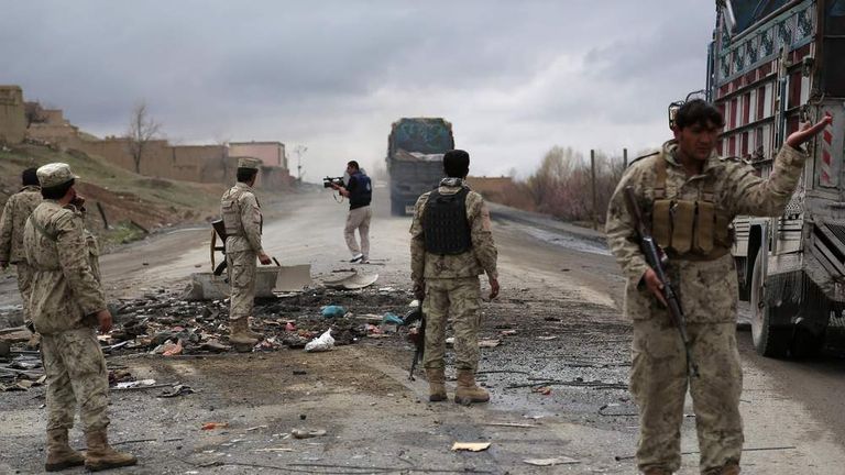 Afghan security forces assess the wreckage of a bomb blast in March