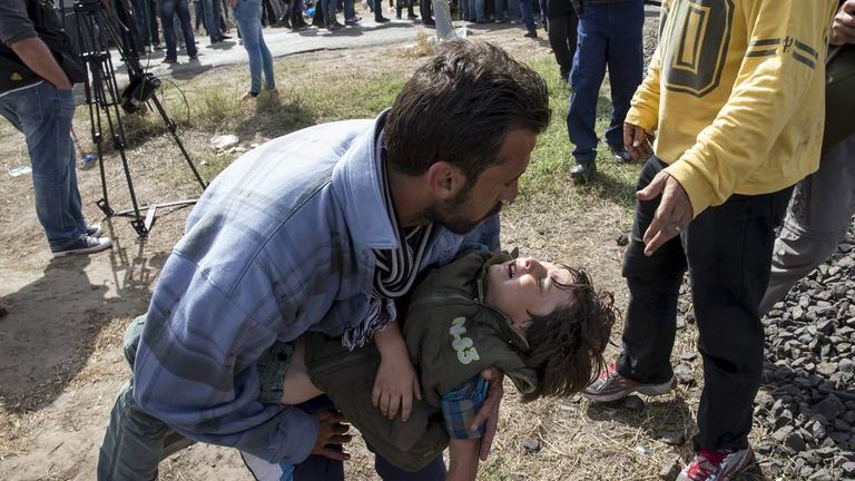 A migrant seeks medical attention for a child suffering from heatstroke at a collection point in the village of Roszke, Hungary