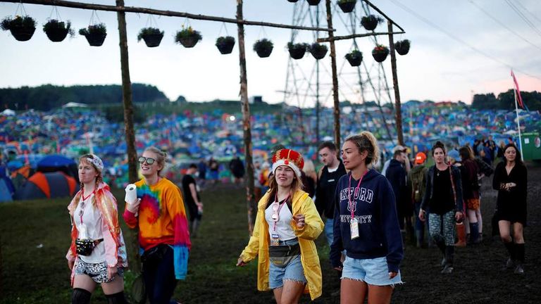 Reveller walk in a field at Worthy Farm in Somerset during the Glastonbury Festival