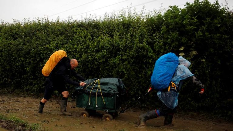 Revellers carry their belongings as they arrive at Worthy Farm in Somerset for the Glastonbury Festival