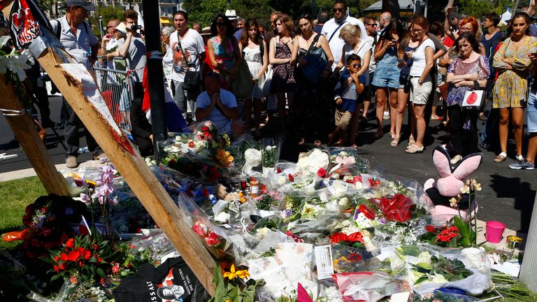 People gather by flowers laid near the scene of the truck attack in Nice