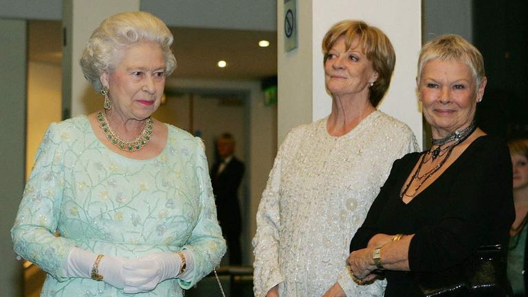 Queen Elizabeth II (L) walks past Dame M