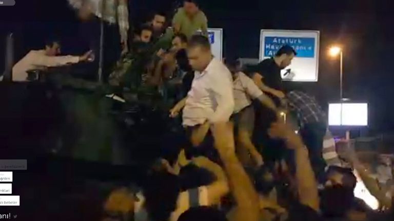 Protesters force their way onto a tank after shots are fired at the crowd