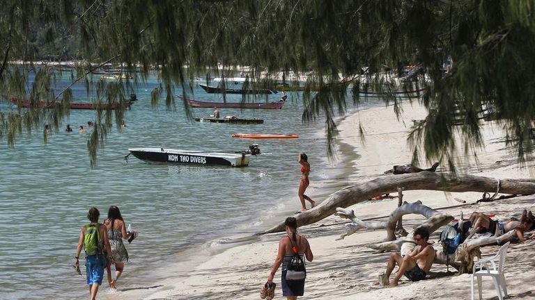 Tourists enjoy the nice weather on a beach near the spot where bodies of two killed British tourists were found,