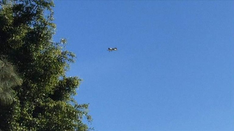 A vintage plane being flown by Harrison Ford comes down on a golf course.