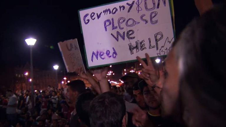 man holds sign asking Germany for help