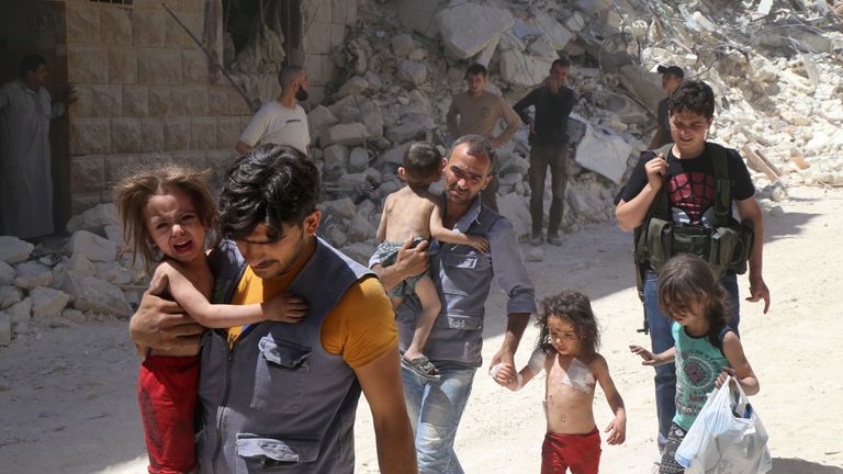 Children are carried amid the rubble of destroyed buildings