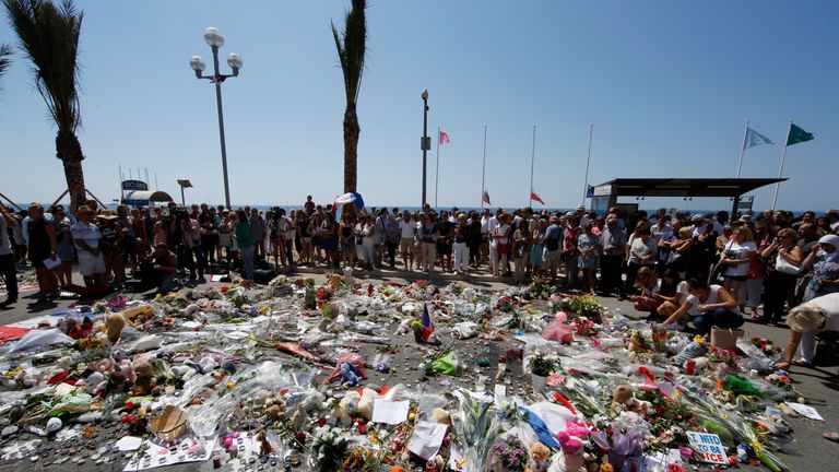 People gather around a makeshift memorial with flowers and candles 