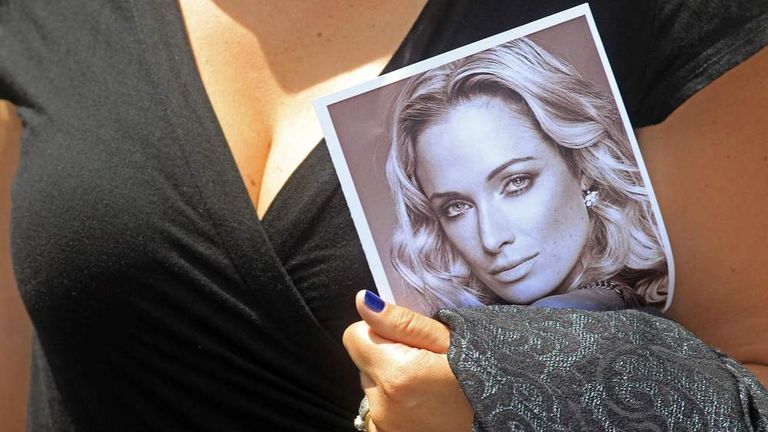 A woman holds a photo of Reeva Steenkamp, as she leaves her funeral