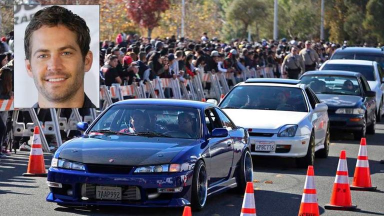 Vehicles are driven past a crowd attending an unofficial memorial event for Fast & Furious star Paul Walker in LA