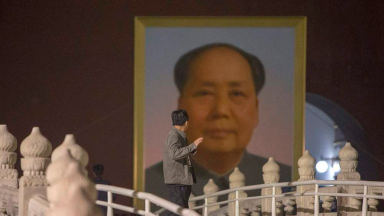 A worker looks at the new portrait of China's late Chairman Mao as it is moved into place to replace the old one at Tiananmen Gate during annual renovation works before the country's national day in Beijing