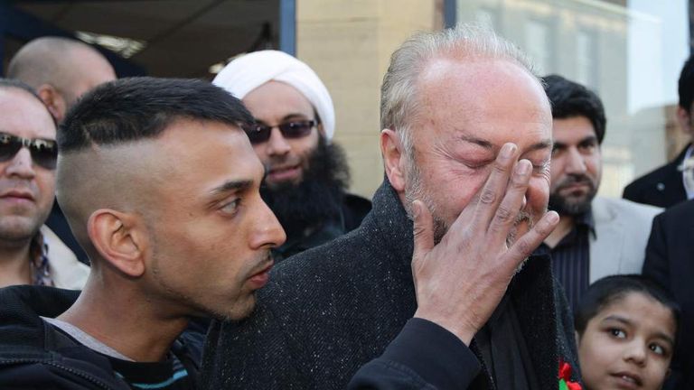 A supporter of MP George Galloway wipes his face after an egg was thrown towards the MP