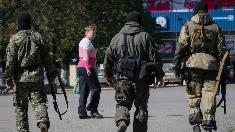 Pro-Russian armed men walk down a street in central Slaviansk