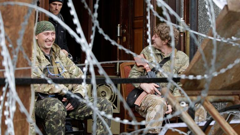 Pro-Russian armed men sit at the entrance to the regional government headquarters in Luhansk