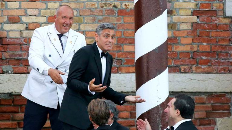 U.S. actor Clooney  gestures as he leaves by taxi boat to travel to the venue of a gala dinner ahead of his official wedding ceremony in Venice