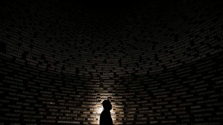 A worker looks at names of the 2004 tsunami victims on a wall at the Aceh Tsunami Museum during preparations for a ceremony in Banda Aceh