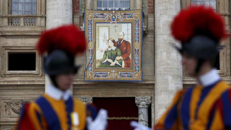 A tapestry showing Louis and Zelie Martin, parents of St. Therese of Lisieux, hangs from a balcony as Pope Francis leads the mass for their canonization in Saint Peter's Square at the Vatican