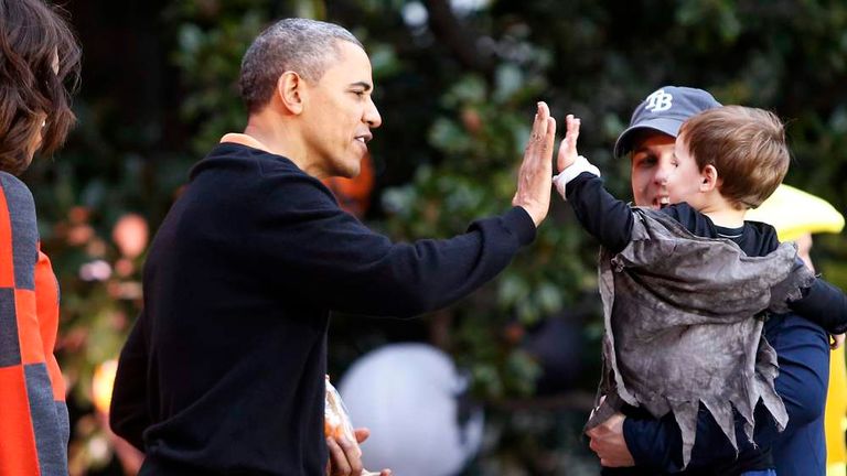 Obama gives a high five as he and first lady give Halloween treats to visiting children at the White House in Washington