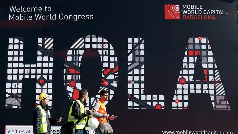 Workers walk past a Mobile World Congress banner in Barcelona