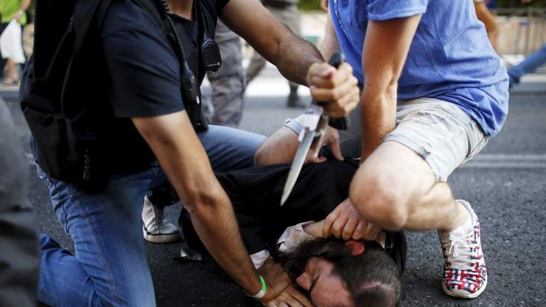 People disarm an Orthodox Jewish assailant shortly after he stabbed participants at the annual Gay Pride parade in Jerusalem.