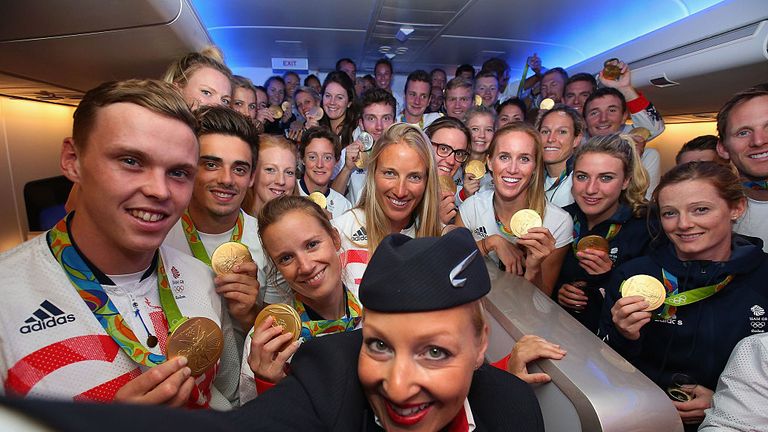A crew member uses a selfie stick to take a photo with Team GB medal winners