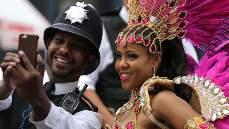 A performer poses for a selfie with a police officer on the second day of the Notting Hill Carnival in west London