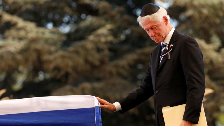 Former U.S. President Bill Clinton touches the flag-draped coffin of former Israeli President Shimon Peres, after eulogising him during his funeral ceremony at Mount Herzl cemetery in Jerusalem