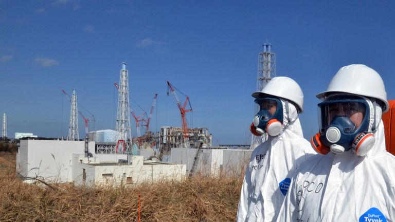 Workers stand on front of the Fukushima power plant months after a meltdown at the site