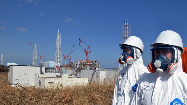 Workers stand in front of the Fukushima nuclear power plant months after the meltdown
