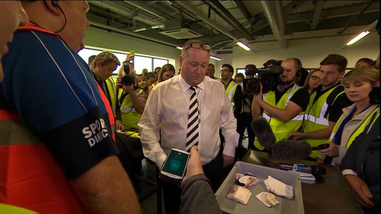 Mike Ashley takes a wad of cash out of his pocket during the Sport Direct tour