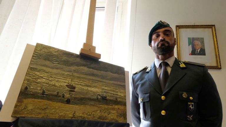 An Italian policeman stands next to The Beach At Scheveningen During A Storm, a Van Gogh painting stolen 14 years ago and found in Italy