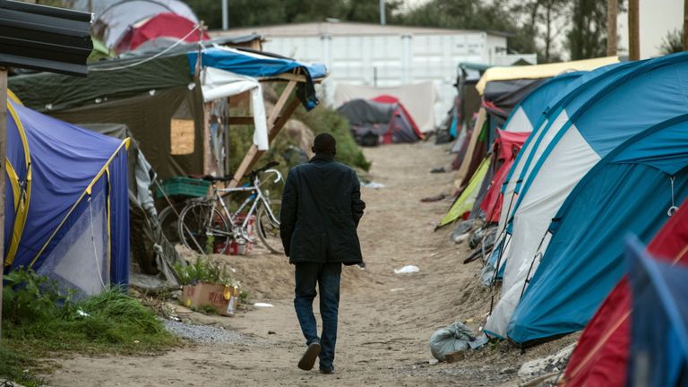 TOPSHOT - A migrant walks on September 26, 2016 in the so-called &#39;Jungle&#39; migrant camp in the French northern port city of Calais. French President Francois Hollande said on a visit to the port of Calais on September 26, 2016 that the sprawling &#39;Jungle&#39; migrant camp would be &#39;definitively dismantled&#39; under a plan to relocate the migrants to centres around the country. Hollande, on his first visit to Calais as president, also called on British authorities to &#39;play their part&#39; in assisting the mig
