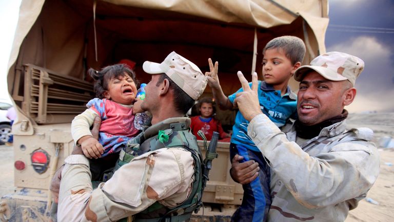 Iraqi army soldiers carry displaced children