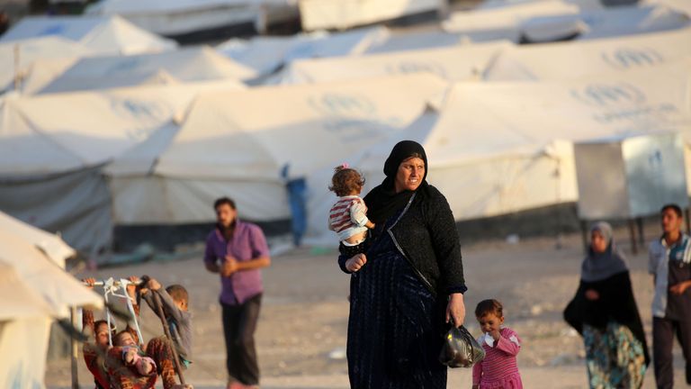 A woman walks with children at a refugee camp housing Iraqi families who fled fighting in the Mosul area in the northeastern town of al-Hol in Syria&#39;s Hasakeh province