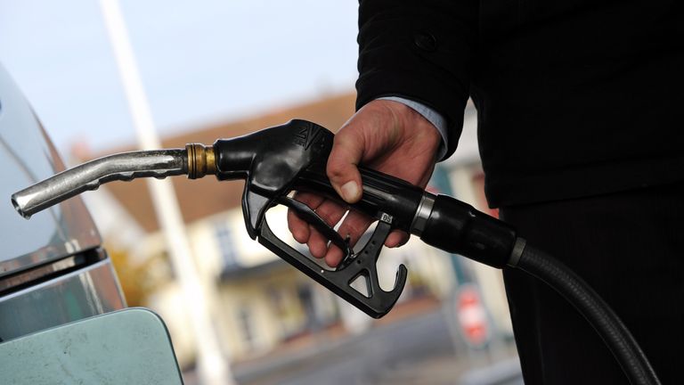A customer pulls the nozzle of a petrol pump from their car 