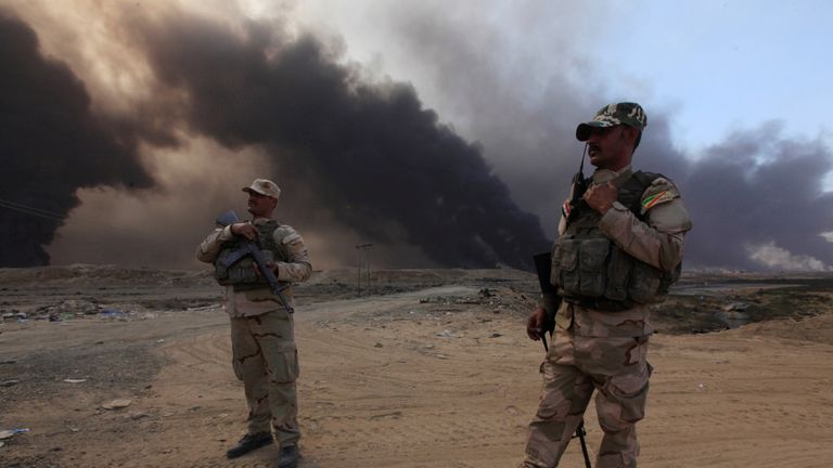 Iraqi army members stand with thier weapons in Qayyarah