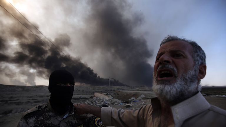 A Sunni fighter from the Popular Mobilisation Forces is welcomed by a an Iraqi man at a checkpoint east of Mosul, as displaced Iraqi families flea areas of unrest
