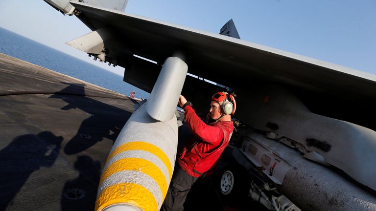 An aviation ordnanceman inspects a bomb on an F/A-18E Super Hornet just before take-off for Mosul