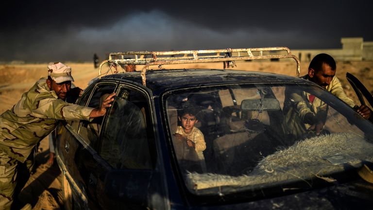 TOPSHOT - An Iraqi forces member helps a displaced man push a car as they arrive at refugee camp on October 22, 2016 in the town of Qayyarah, south of Mosul, as an operation to recapture the city of Mosul from the Islamic State group takes place. Iraqi security forces battled for a second day with Islamic State group gunmen who infiltrated Kirkuk in a brazen raid that rattled Iraq as it ramped up an offensive to retake Mosul