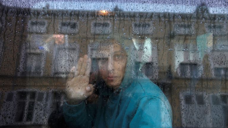 An Afghan adolescent migrant waves from a van as he departs with six others from the emergency shelter for minors in Saint Omer, France as they leave for Britain 