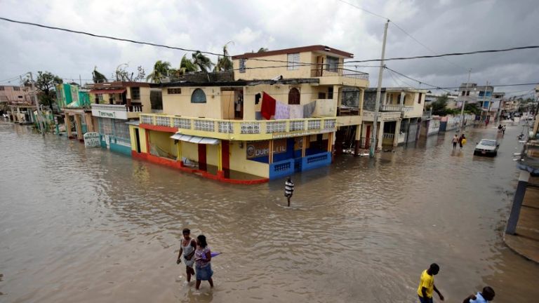People walk in a flooded area after Hurricane Matthew in Les Cayes, Haiti