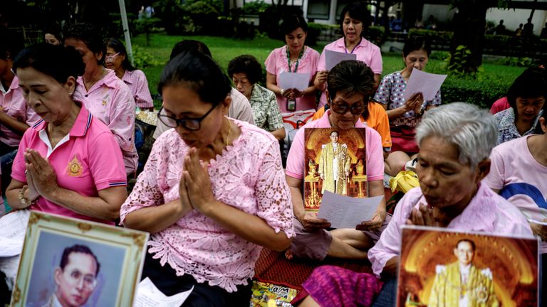 Well-wishers hold pictures of Bhumibol Adulyadej as they pray for him. 