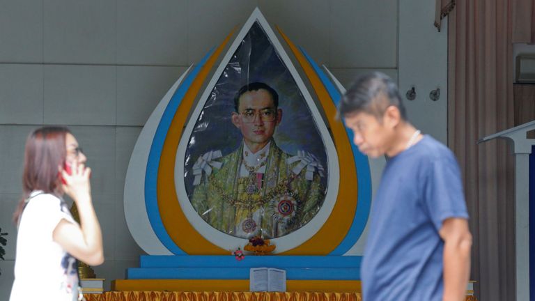 People walk past a picture of King Bhumibol Adulyadej at Siriraj Hospital