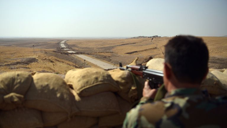A Kurdish peshmerga soldier aims his rifle toward a road to Mosul as forces continue the battle