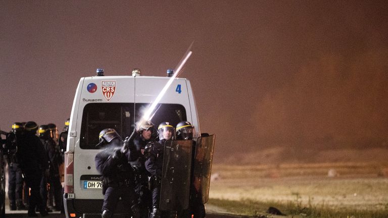 French riot police fired tear gas to disperse migrants throwing stones and lighting fires