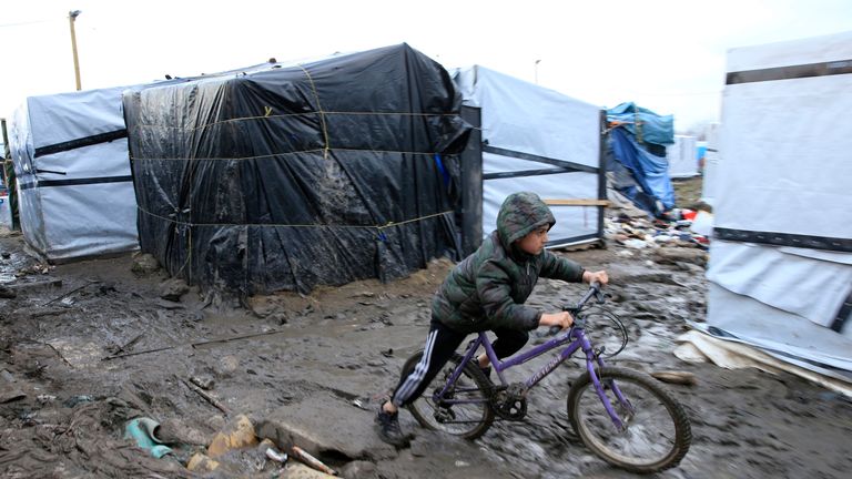 A young boy from Afghanistan pushes his bycicle in the mud in the southern part of the camp known as the "Jungle", a squalid sprawling camp in Calais, northern France, February 25, 2016. A French judge on Thursday upheld a government plan to partially demolish a shanty town for migrants trying to reach Britain on the outskirts of the northern port of Calais, an official spokesman said. REUTERS/Pascal Rossignol