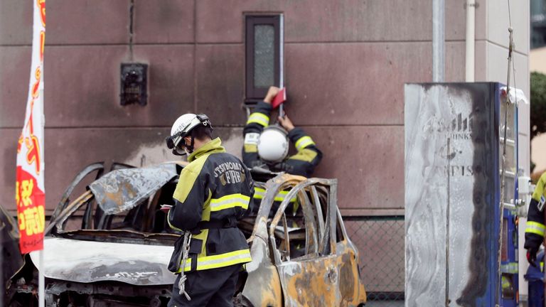 Firefighters investigate a burnt car at the site of an explosion in Utsunomiya, Japan. Pic: Kyodo/via Reuters